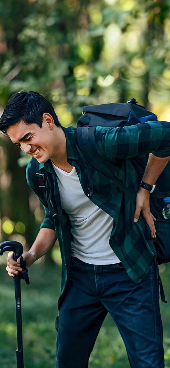 Asian man holding back in pain and in hiking gear